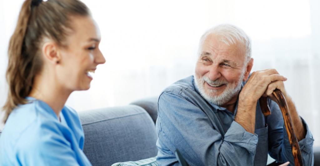 Eine junge Pflegefachkraft der IAHA im Gespräch mit einem älteren Mann – ein Beispiel für die wertvolle Unterstützung, die pflegende Angehörige im Alltag entlastet.